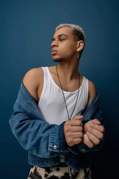 Un joven afroamericano muestra una chaqueta de mezclilla de moda y un estilo único. - foto de stock
