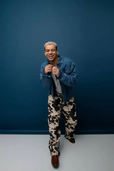 Un joven afroamericano con el pelo teñido muestra un atuendo de moda, exudando confianza. - foto de stock