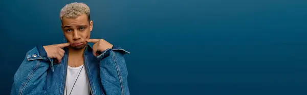 Un joven negro muestra su estilo con el pelo teñido y una chaqueta de mezclilla, pancarta - foto de stock