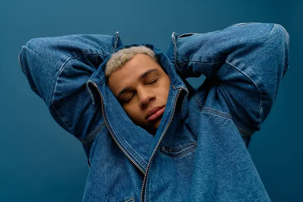 A young african american man with dyed hair strikes a fashionable pose in a denim jacket. — Stock Photo