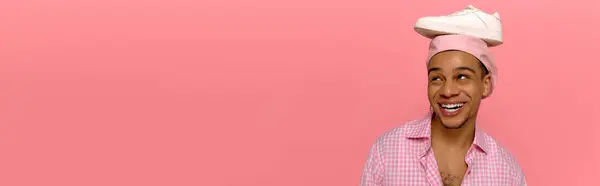 A confident young man in a checkered shirt and beret proudly poses against a cheerful pink backdrop, banner — Stock Photo