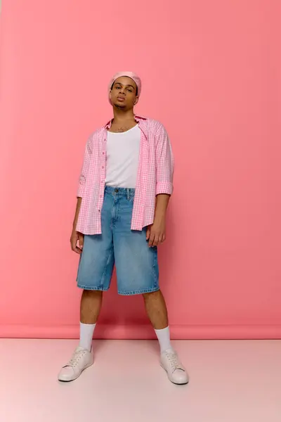 A stylish young Black man poses confidently against a vibrant pink background. — Stock Photo