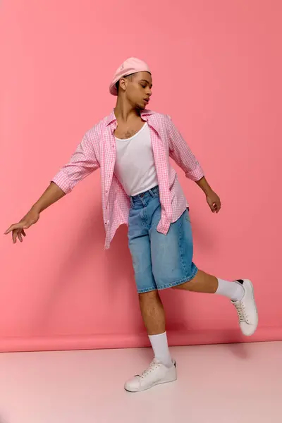 A young Black man in a checkered shirt and beret poses against a bright pink background. — Stock Photo