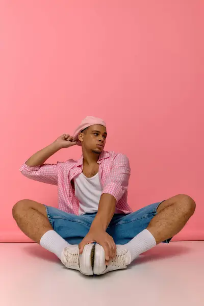 Ein junger Afroamerikaner präsentiert seinen modischen Look mit Baskenmütze und kariertem Hemd. — Stockfoto