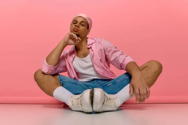 A confident young man relaxes in a trendy outfit, showcasing his unique style and personality. — Stock Photo