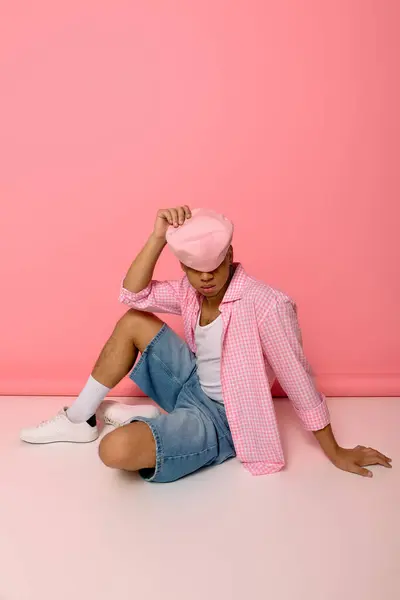 A young African American man poses confidently on the floor in a stylish checkered shirt and beret. — Stock Photo