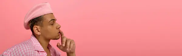 Un giovane uomo afroamericano elegante posa pensieroso contro uno sfondo rosa brillante, banner — Foto stock