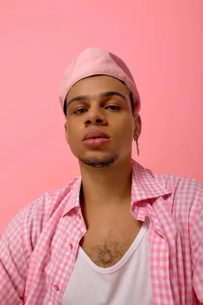 A young African American man poses confidently on a vivid pink backdrop, showing his fashion sense. — Stock Photo