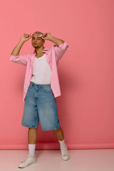 Un joven afroamericano exhibe un look moderno con una camisa a cuadros y gafas de sol. - foto de stock