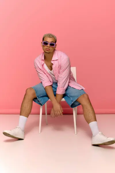 Un joven negro muestra juguetonamente su camisa a cuadros de moda y sus gafas de sol. - foto de stock
