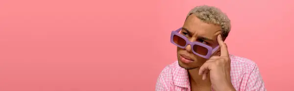 Un joven afroamericano posa con confianza, luciendo una camisa a cuadros y gafas de sol juguetonas, pancarta - foto de stock