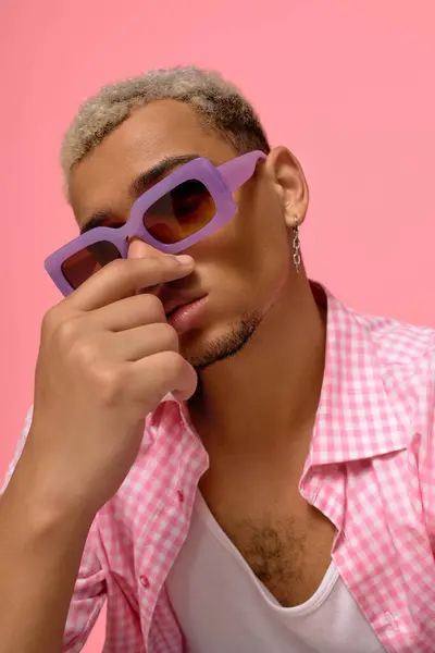 Un jeune homme branché met en valeur son style vibrant avec des cheveux teints et des lunettes de soleil. — Photo de stock