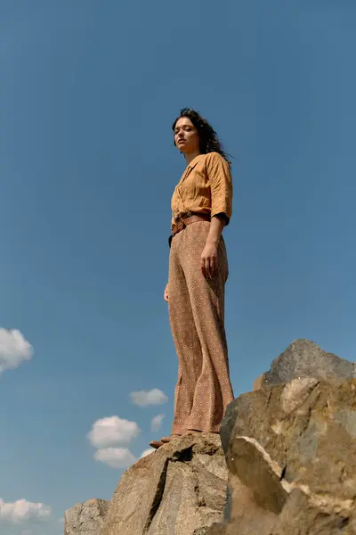 A young woman with curly hair poses confidently outdoors in a stylish outfit. — стоковое фото