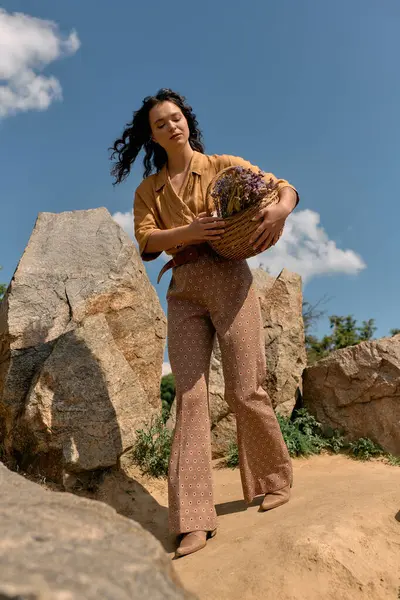 En un entorno al aire libre vibrante, una mujer joven muestra su elegante aspecto de verano mientras sostiene flores. - foto de stock