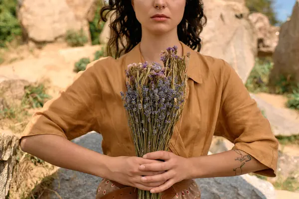 Young woman with curly hair poses outdoors with a bouquet of dried flowers in nature. — стоковое фото