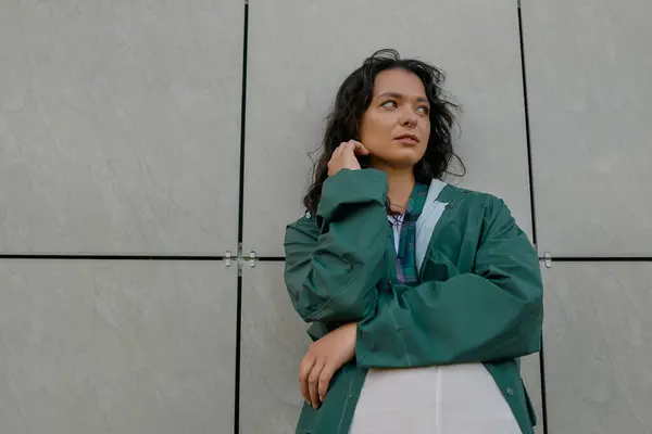 Una mujer joven con estilo posa con confianza en un impermeable de moda al aire libre, abrazando vibraciones de verano. - foto de stock