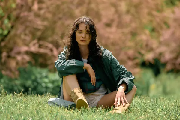 Curly-haired woman models her stylish raincoat while enjoying a sunny day outside. — стокове фото