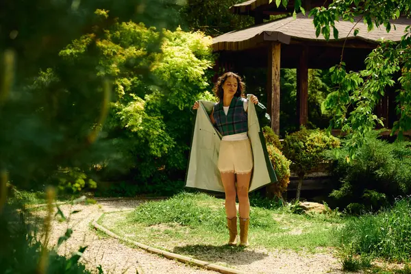 A young woman showcases her trendy raincoat while enjoying a sunny summer day in nature. — Stock Photo