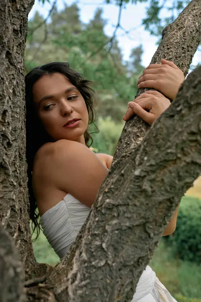 A young woman with curly hair poses gracefully in a white dress on a sunny summer day. — стокове фото