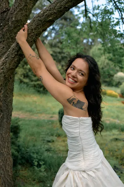 A young woman in a white dress joyfully poses under the summer sun amid greenery. — Stock Photo