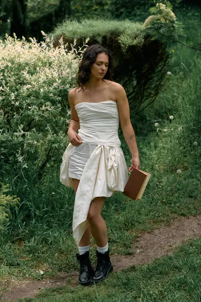 A young woman with curly hair poses gracefully outdoors on a sunny day, dressed in white. — стоковое фото