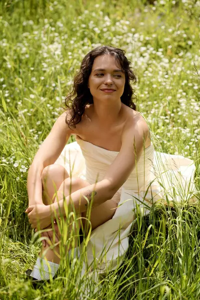 A young woman with curly hair relaxes in a meadow, soaking up the sun among blooming flowers. — Fotografia de Stock