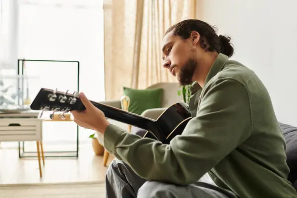 Handsome young man engages in music making while relaxing at home, enjoying a peaceful moment. — Stock Photo