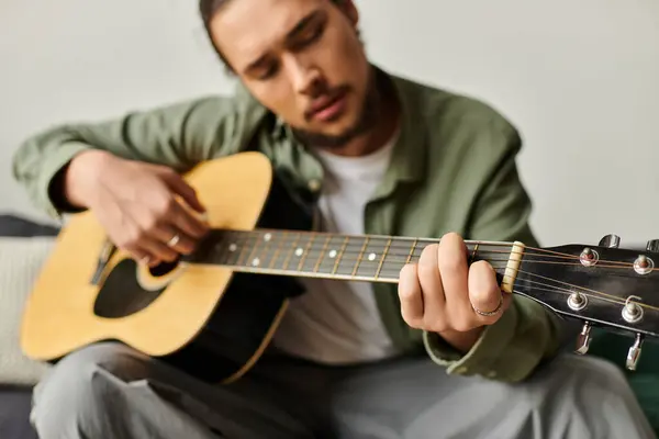 Ein junger Mann spielt zu Hause seine Gitarre, verloren in der Freude an Musik und Kreativität. — Stockfoto
