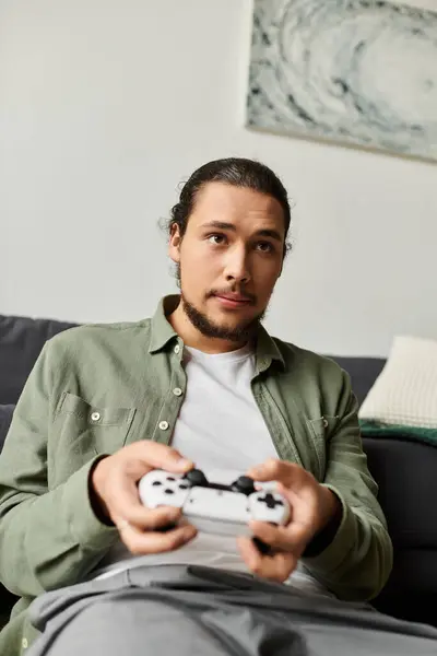 Young man relaxes at home, focused intently on a video game while holding a controller. — Stock Photo