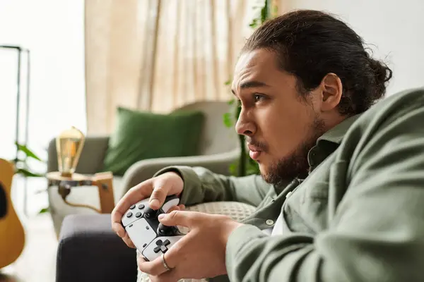 A young handsome man immerses himself in gaming at home, focused and serious about winning. — Stock Photo
