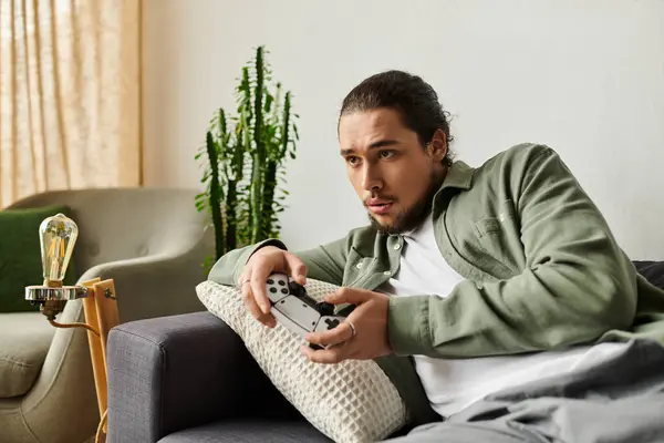 Focused giovane uomo gioca ai videogiochi a casa, circondato da arredamento moderno e verde. — Foto stock