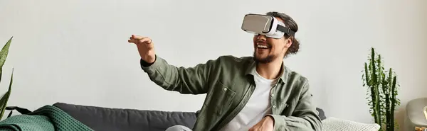 Joyful young man immersed in a virtual adventure while relaxing on his couch in his cozy home. — Stock Photo