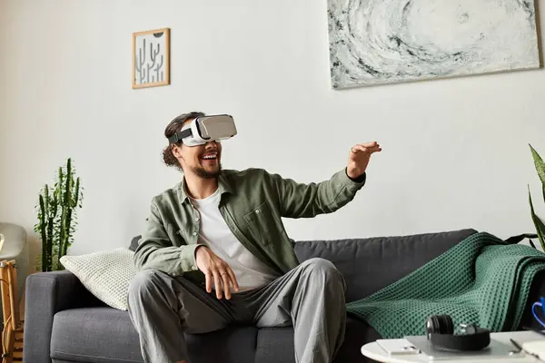 Young man at home engages with virtual reality, expressing joy and immersive enjoyment. — Stock Photo