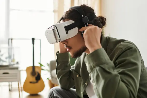 A young man explores a virtual world in VR while relaxing in his living room. — Stock Photo