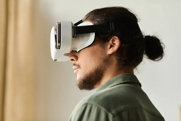 A young handsome man is deeply focused on an immersive virtual reality activity at home. — Stock Photo