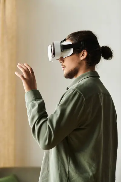 Handsome man experiences virtual reality while gesturing in a cozy living space filled with light. — Stock Photo