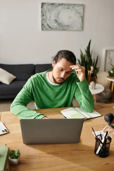 Young man with a contemplative expression working intently at his desk in a cozy home setting. — Stock Photo