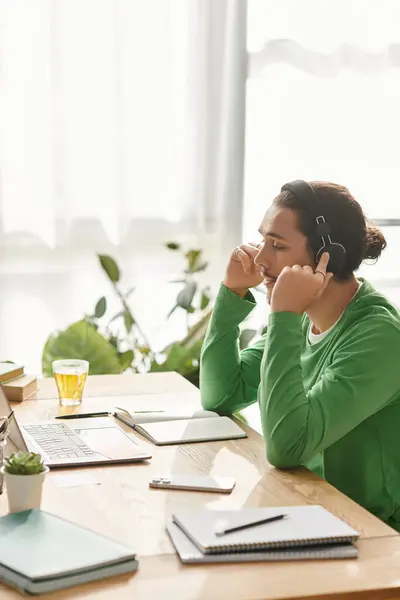 A handsome young man is focused on his work in a bright, cozy room with headphones on. — Stock Photo