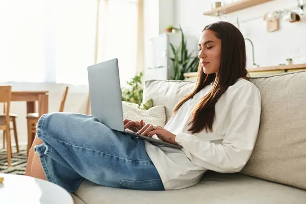 Young woman enjoys her time at home, focused on her laptop in a comfy living area. — Stock Photo