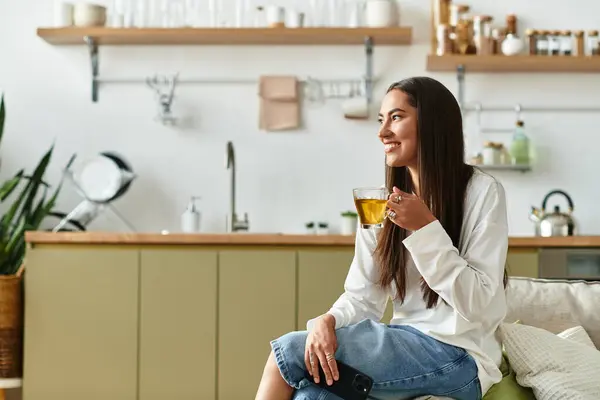 Giovane donna assapora un momento di tranquillità a casa sorseggiando una bevanda calda e sorridendo. — Foto stock