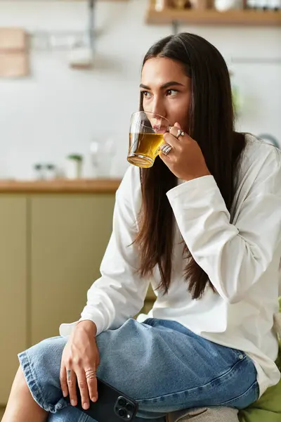 A beautiful young woman relaxes at home, sipping tea while embracing a comfy atmosphere. — Stock Photo