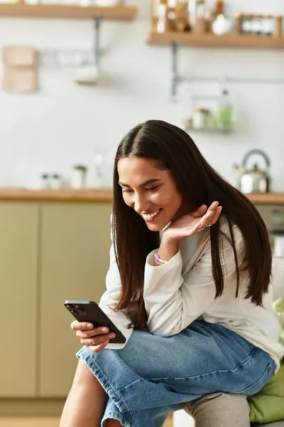 Beautiful woman relaxes in her cozy home, smiling while browsing her smartphone. — Stock Photo