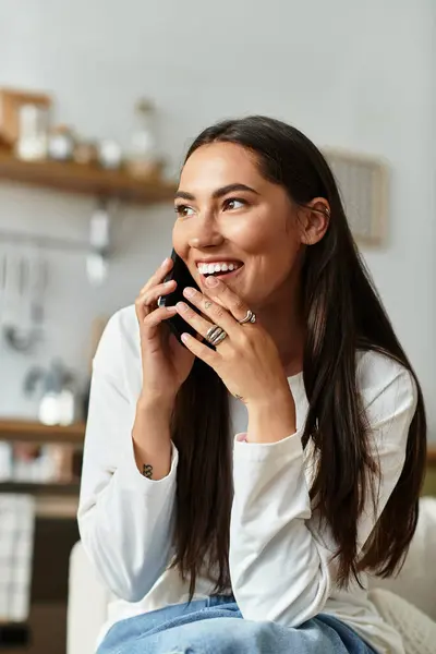 Pretty woman relaxed at home, smiling and engaging in a cheerful phone conversation. — Stock Photo