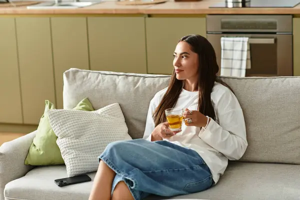 Una giovane bella donna si gode il suo tè caldo mentre si riposa comodamente a casa in un'atmosfera accogliente. — Foto stock