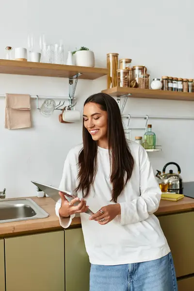 Beautiful woman relaxes in her stylish kitchen, engaged in cooking and enjoying her time. — Stock Photo