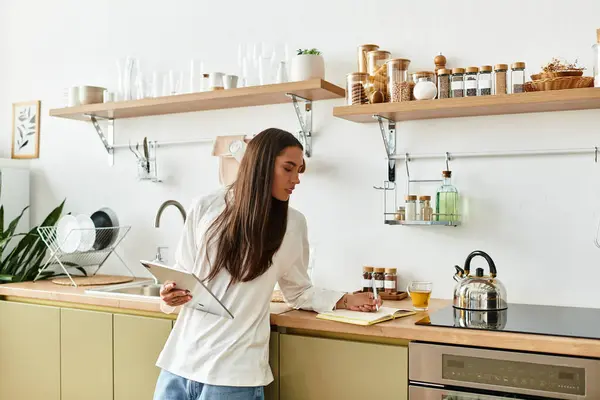 A pretty woman engages in a creative activity at her comfortable kitchen space, taking notes. — Stock Photo