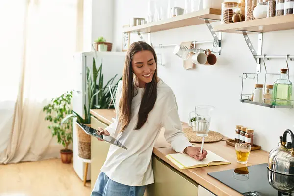 Cozy atmosphere fills the home as a woman writes in her journal, enjoying a refreshing drink. — Stock Photo