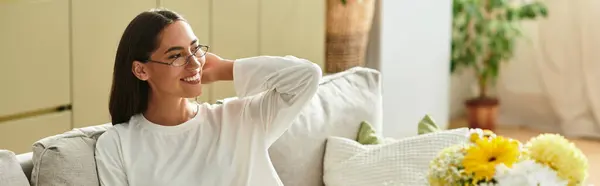 Relaxing in a comfortable setting, a beautiful young woman smiles as she embraces her cozy space. — Stock Photo
