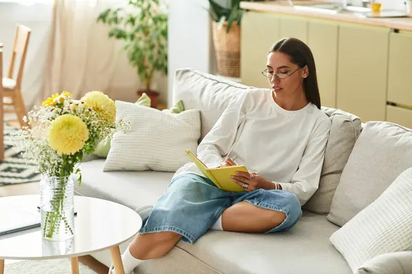 Comfy setting with a beautiful woman writing in her journal, surrounded by peaceful home decor. — Stock Photo
