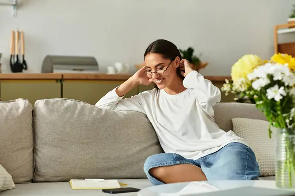 A cheerful young woman relaxes on a comfy sofa at home, enjoying her peaceful afternoon. — Stock Photo